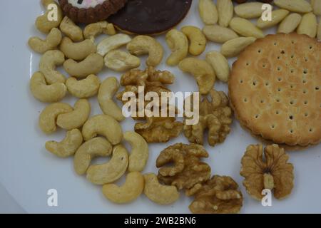 Gesunde und gesunde Lebensmittel, Snacks, viele natürliche Nüsse: Cashews, Mandeln, Walnüsse, Haselnüsse und Kekse auf einer weißen Glasplatte. Stockfoto
