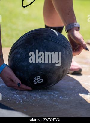 Eine Frau, die einen schwarzen, gewichteten Ball in der Hand hält Stockfoto