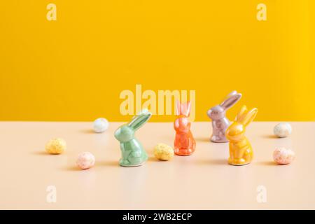 oster-Konzept im Hintergrund. Bunte Eier und Kaninchen auf Gelb. Stockfoto