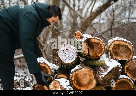 Mann, der mit Schnee bedeckten Holzscheite hält, um Brennholz zu verwenden Stockfoto