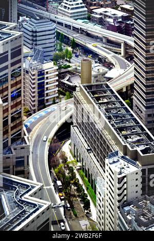 Blick aus der Vogelperspektive auf die Stadt Tokio mit einer großen Autobahn, die durch eine Ansammlung von Hochhäusern in üppigem Grün verläuft Stockfoto