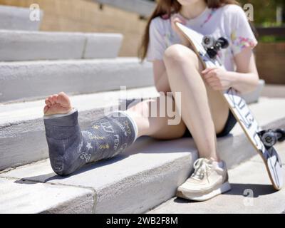 Ein junges Mädchen mit Beinbesatz und Skateboard Stockfoto