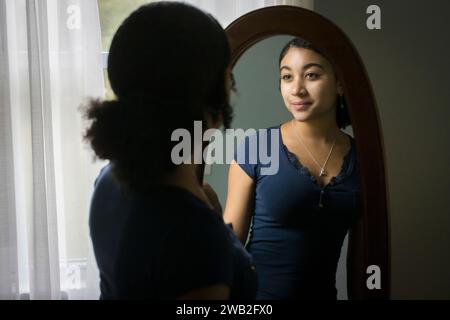 Birassisches Teenager-Mädchen schaut sich Hersef im Spiegel an Stockfoto