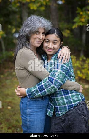 Porträt der weißen Mutter und ihrer zweirassigen Teenager-Tochter, die sich umarmen Stockfoto