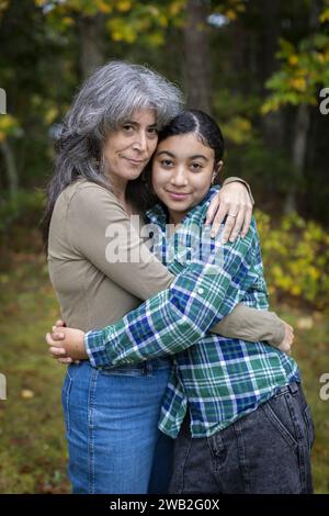 Porträt der weißen Mutter und ihrer zweirassigen Teenager-Tochter, die sich umarmen Stockfoto