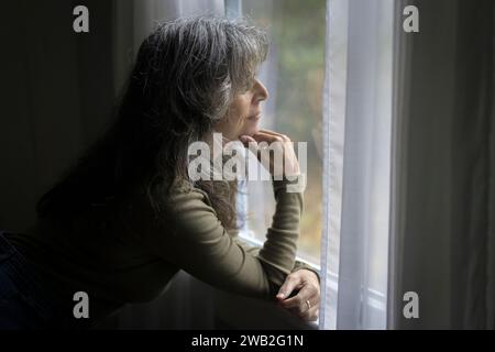 Ältere weiße Frau im Profil schaut aus dem Fenster Stockfoto