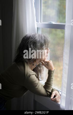 Ältere weiße Frau im Profil schaut aus dem Fenster Stockfoto