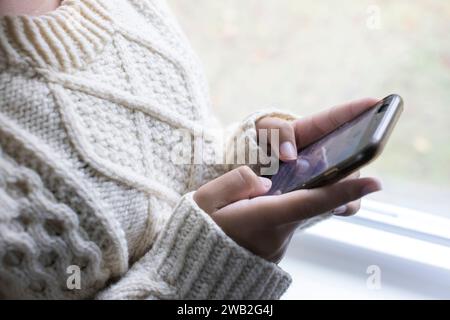 Nahaufnahme der Hände eines birassischen Teenager-Mädchens, die auf dem Handy schreiben Stockfoto