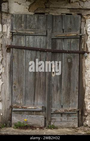 Sunja, Kroatien, 05.04.2021: Alte rustikale Holztür an ländlicher Hauswand. Stockfoto