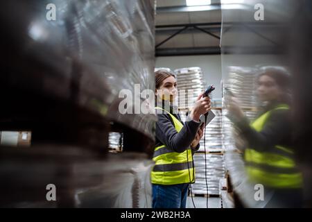 Weibliche Lagerarbeiterin, die einen Scanner hält und die Barcodes auf Produkten im Lager scannt. Lagermanager, der das Lagerscansystem verwendet. Stockfoto