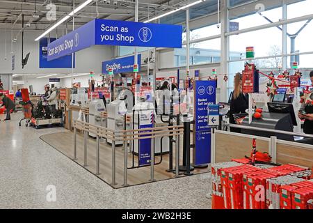 Scannen Sie beim Einkaufen von Schildern bei Käufern Kassen-Zahlungsbereich Kunden, die im Tesco Extra Supermarkt, einem Einzelhandelsunternehmen London England Großbritannien, einkaufen Stockfoto