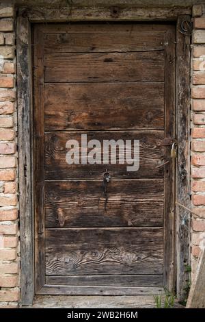 Sunja, Kroatien, 05.04.2021: Alte rustikale Holztür an ländlicher Hauswand. Stockfoto