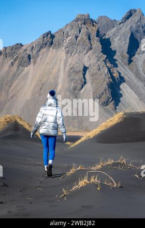 Eine junge kaukasische Frau posiert am Strand mit schwarzem Sand Stockfoto