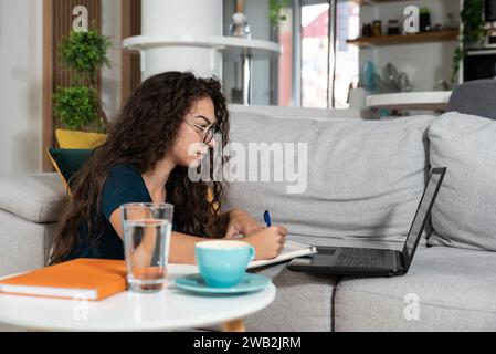 Junge kranke Schulmädchen oder Studentinnen, die online Hausaufgaben machen oder Schulprüfungen für das College machen, mit Laptop-Computer. Ein kranker Teenager arbeitet bei Schulprofis Stockfoto