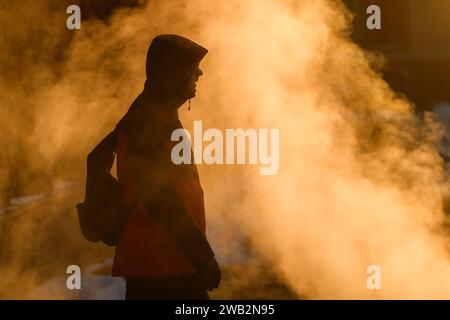 RIGA, Lettland. Januar 2024. Foto mit selektivem Fokus. Die Person läuft auf dem Bürgersteig. Sonnenaufgang über Riga. Eisige Polarkälte bringt Temperaturen von minus 21 Grad in Riga, während -28 am Flughafen Riga lag. Quelle: Gints Ivuskans/Alamy Live News Stockfoto