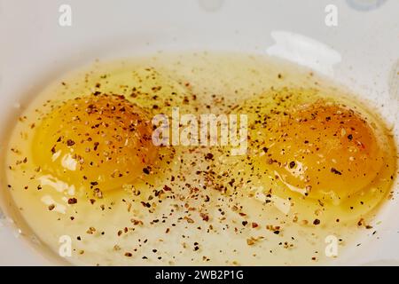 Zwei rohe Eier auf einem Teller mit Gewürzen darauf. Stockfoto