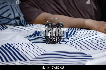 Schwarzer Wecker im Bett. Zeit zum Aufwachen Stockfoto