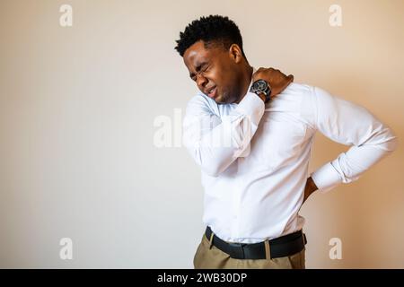 Porträt eines jungen Geschäftsmannes, der Schmerzen im Rücken hat. Kopieren Sie einen Platz auf dem Bild für Ihren Text oder Ihre Werbung. Stockfoto