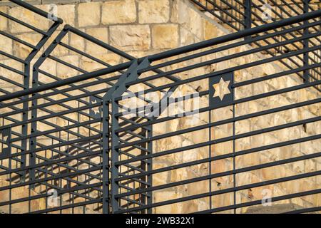 Fokussierte Ansicht eines Davidsterns, sichtbar auf einer Metallbarriere, die jüdische Identität vor einem Hintergrund aus veraltetem Stein symbolisiert Stockfoto