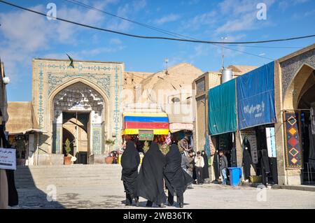 Rücken von drei in Tschador gekleideten Frauen vor dem Eingang der Jameh-Moschee von 771 n. Chr. und den Kuppeln des Großen Basars von Isfahan. Isfahan, Iran. Stockfoto