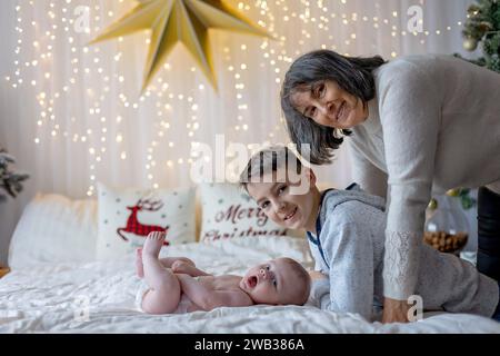 Glückliche Familie, neugeborenes Baby und ältere Brüder, Mutter zu Hause zu Weihnachten Stockfoto