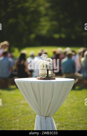 Eine vertikale von einem Tisch mit einer Vase voller Blumen in einem Park bei einer Hochzeit Stockfoto