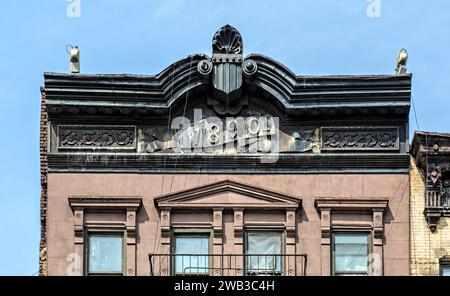 Ein gestempeltes Metallgesims überragt die 1968 Third Avenue, ein fünfstöckiges Wohnhaus aus Backstein und Brownstone mit Geschäften aus dem Jahr 1890. Stockfoto