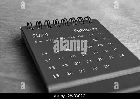 Schwarz-weißer Schreibtischkalender vom Februar 2024 auf Holzschreibtisch. Kalender- und Neumonatskonzept. Stockfoto