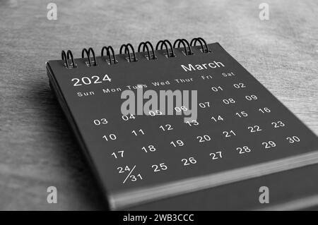 Schwarz-weißer Schreibtischkalender vom März 2024 auf Holzschreibtisch. Neues Monatskonzept Stockfoto