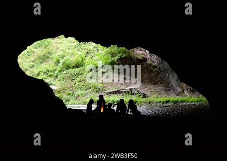 Die Silhouetten der Menschen sitzen am Feuer in einer Höhle Stockfoto