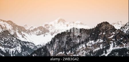Ein Panoramablick auf die bayerischen Alpen, bedeckt mit einer Schneedecke und beleuchtet von der beeindruckenden Präsenz von Sahara-Staub Stockfoto