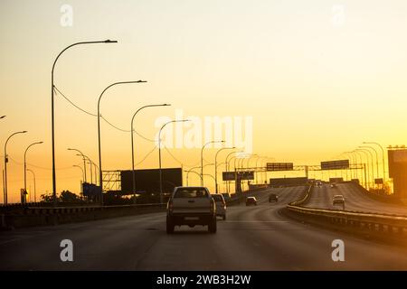 Autos, die eine ruhige Autobahn hinunterfahren, bis in die Morgenröte an einem Wochenende in Johannesburg, Südafrika, Stockfoto