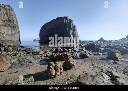 Felsige Küste mit großen, zerklüfteten Formationen, die unter einem klaren Himmel in asturien aus dem Meer ragen Stockfoto