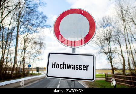 Sandkrug, Deutschland. Januar 2024. Vor einer gesperrten Straße steht ein Schild mit der Aufschrift „Hochwasser“. Der anhaltende Regen und das hohe Wasser haben die umliegenden Wiesen und Felder in der Nähe der Hunte überflutet. Quelle: Hauke-Christian Dittrich/dpa/Alamy Live News Stockfoto