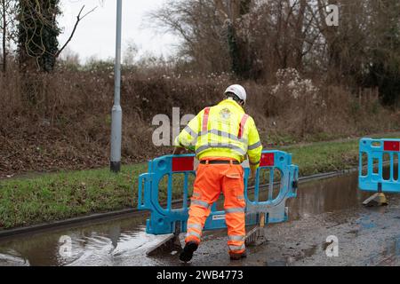 Horton, Wraysbury, Berkshire, Großbritannien. Januar 2024. Ein Mann aus dem Royal Borough of Windsor & Maidenhead errichtet Barrieren, um eine Straße wegen Überschwemmungen in Horton, Wraysbury Berkshire, zu schließen. Die Themse ist über die Ufer geplatzt und es gibt eine Reihe von Straßensperren in der Umgebung. Quelle: Maureen McLean/Alamy Live News Stockfoto