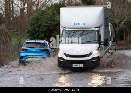 Horton, Wraysbury, Berkshire, Großbritannien. Januar 2024. Autofahrer fahren auf einer Landstraße in Horton, Wraysbury, Berkshire, durch Hochwasser. Die Themse ist über die Ufer geplatzt und es gibt eine Reihe von Straßensperren in der Umgebung. Quelle: Maureen McLean/Alamy Live News Stockfoto