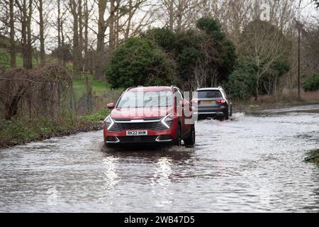 Horton, Wraysbury, Berkshire, Großbritannien. Januar 2024. Autofahrer fahren auf einer Landstraße in Horton, Wraysbury, Berkshire, durch Hochwasser. Die Themse ist über die Ufer geplatzt und es gibt eine Reihe von Straßensperren in der Umgebung. Quelle: Maureen McLean/Alamy Live News Stockfoto