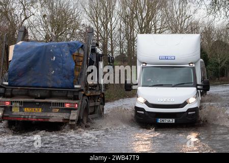 Horton, Wraysbury, Berkshire, Großbritannien. Januar 2024. Autofahrer fahren auf einer Landstraße in Horton, Wraysbury, Berkshire, durch Hochwasser. Die Themse ist über die Ufer geplatzt und es gibt eine Reihe von Straßensperren in der Umgebung. Quelle: Maureen McLean/Alamy Live News Stockfoto