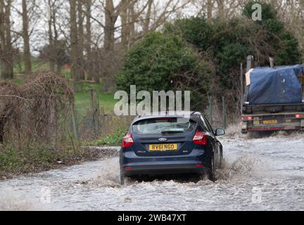 Horton, Wraysbury, Berkshire, Großbritannien. Januar 2024. Autofahrer fahren auf einer Landstraße in Horton, Wraysbury, Berkshire, durch Hochwasser. Die Themse ist über die Ufer geplatzt und es gibt eine Reihe von Straßensperren in der Umgebung. Quelle: Maureen McLean/Alamy Live News Stockfoto