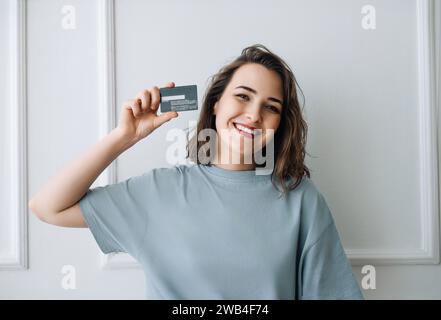 Positive Frau mittleren Alters zeigt Kreditkarte in Close-up Studio-Aufnahme. Happy Lady mittleren Alters präsentiert Kreditkarte, Studio-Nahaufnahme. Mittleres Alter Stockfoto
