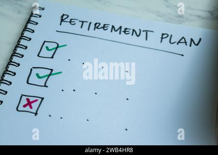 Konzept des Altersvorsorgeplans schreiben im Buch. Unterstützt durch einen zusätzlichen Service isoliert auf Holztisch. Stockfoto