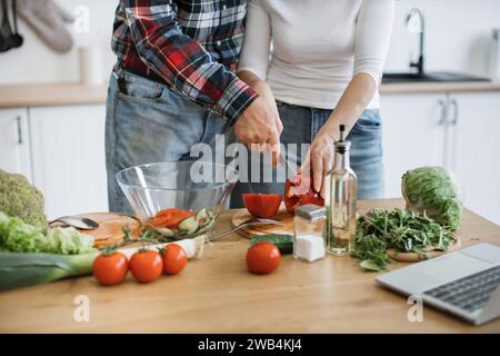 Zugeschnittene Ansicht der Hände eines pensionierten Paares, das Pfeffer schneidet, während das Messer in den Händen zusammengehalten wird Stockfoto