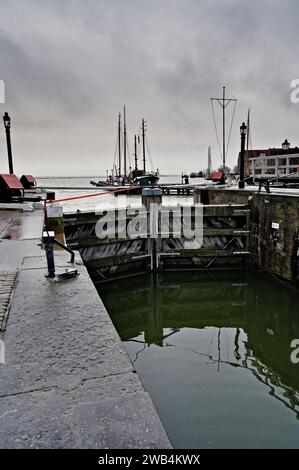 National Monument Inland Harbour Lock geschlossen, verstärkt mit Spanngurten, um Überschwemmungen von Markermeer, graue dramatische Wolken über dem See zu verhindern. Stockfoto