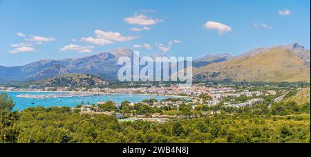 Panoramablick auf Port de Pollenca, eingebettet in die Serra de Tramuntana, mit azurblauem Wasser und einem lebendigen Yachthafen - ein Juwel in Mallorcas Krone. Stockfoto