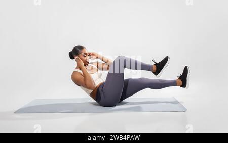 Gute schwarze Frau in Sportbekleidung, die Bauchfahrradtraining macht, Studio Stockfoto