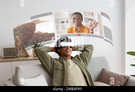Virtual Reality schließt eine Lücke, während der junge Schwarze mit VR-Brillen lebensechte Video-Chats bequem von zu Hause aus genießt Stockfoto