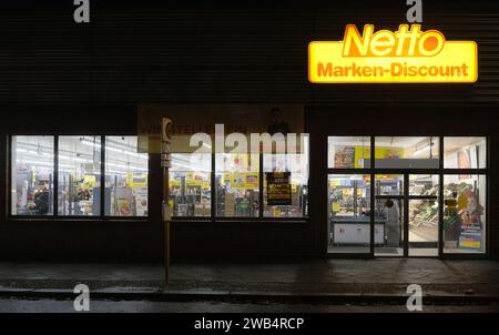 Berlin, 20. Dezember 2023, Eingangsbereich des Netto-Supermarktes in der Sklalitzer Straße bei Nacht mit beleuchtetem Logo und Blick in den Verkauf Stockfoto