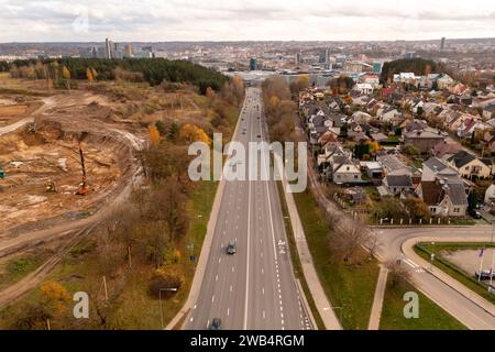 Drohnenfotografie einer hochintensiven Straße in einer Stadt und Stadtlandschaft im Hintergrund während des sonnigen Herbsttags Stockfoto