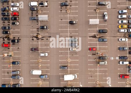 Drohnenfotografie eines großen, halbvollen Parkplatzes in der Nähe eines Einkaufszentrums während des sonnigen Herbsttags Stockfoto
