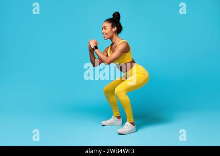 Slim Black Woman Macht Deep Squat Über Blue Studio Stockfoto